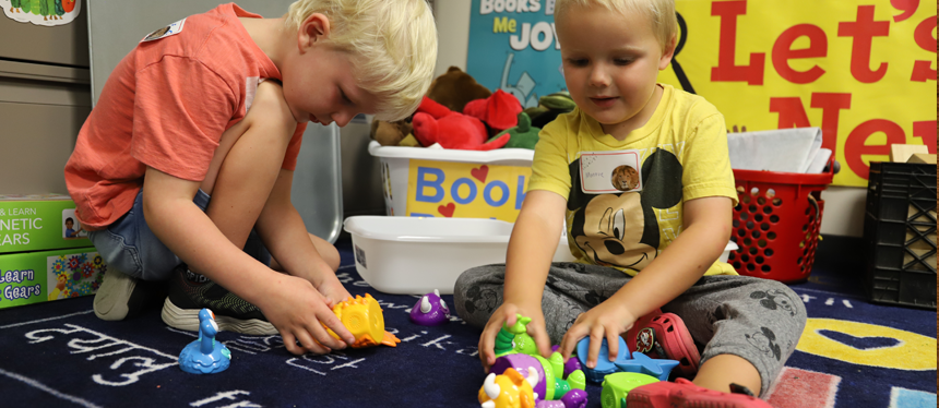 Two children engage with educational resources on a navy activity mat during an LRC-South Family Event. 