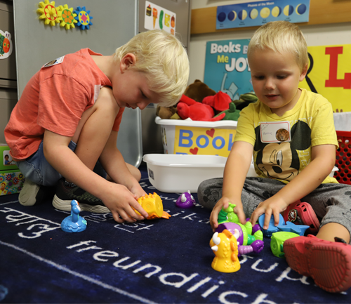 Two children engage with educational resources on a navy activity mat during an LRC-South Family Event