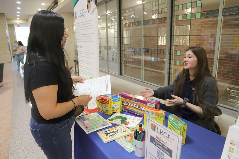 LRC-South staff member sits at a table talking with a March Mixer participant. 